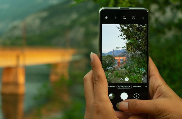 Handy fotografiert eine Landschaft mit Brücke