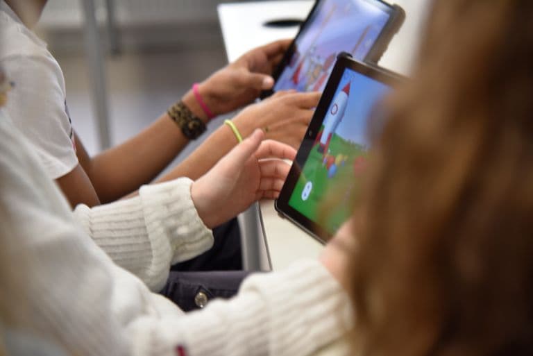 Mehrere Menschen sitzen in einer Reihe vor iPads.